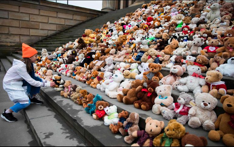 Un niño coloca on oso de peluche, uno de los 740, en las escaleras del salón de conciertos en Berlín. La intervención, organizada por World Vision, busca llamar la atención sobre los 740 mil niños sirios desplazados en siete años de guerra. AFP/O. Andersen