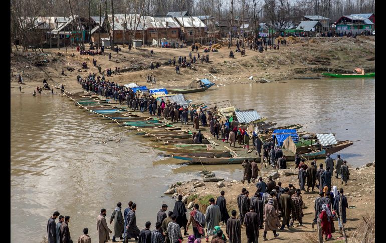 Habitantes de una villa en Cachemira caminan sobre un puente improvisado con botes para acudir al funeral de un líder rebelde asesinado en la región que se disputan India y Pakistán. AP / D. Yasin