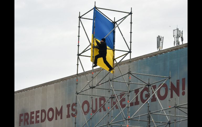 Un manifestante desmonta una estructura de metal en Kiev, durante una protesta para exigir la salida del presidente ucraniano. La estructura se había colocado días antes para decorar la plaza de la Independencia. AFP/G. Savilov