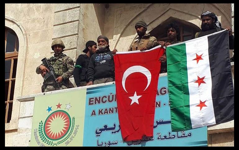 Subidos al balcón de un edificio público, soldados ondearon la bandera turca junto a la del Ejército Libre Sirio. AP/DHA-Depo Photos