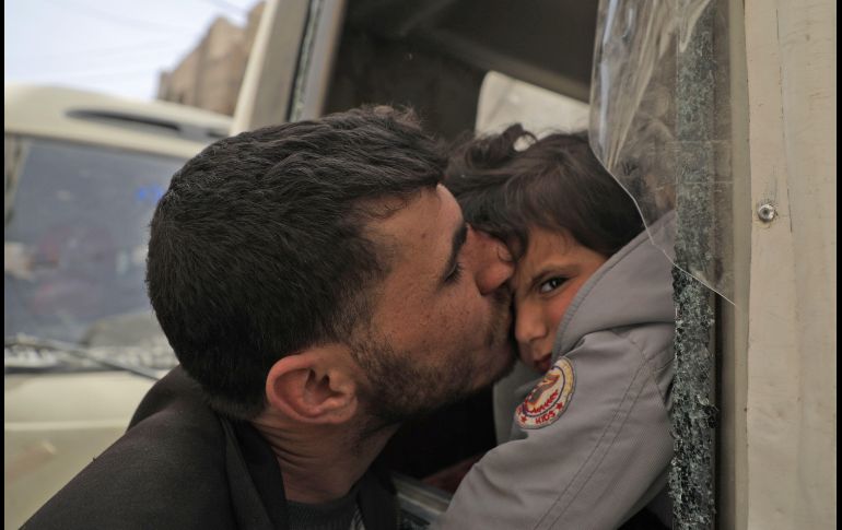 Un hombre besa a un niño mientras civiles suben a camiones de la Media Luna Roja siria, para evacuar a pacientes en estado crítico de la zona de Douma. AFP/H. Al-Ajweh