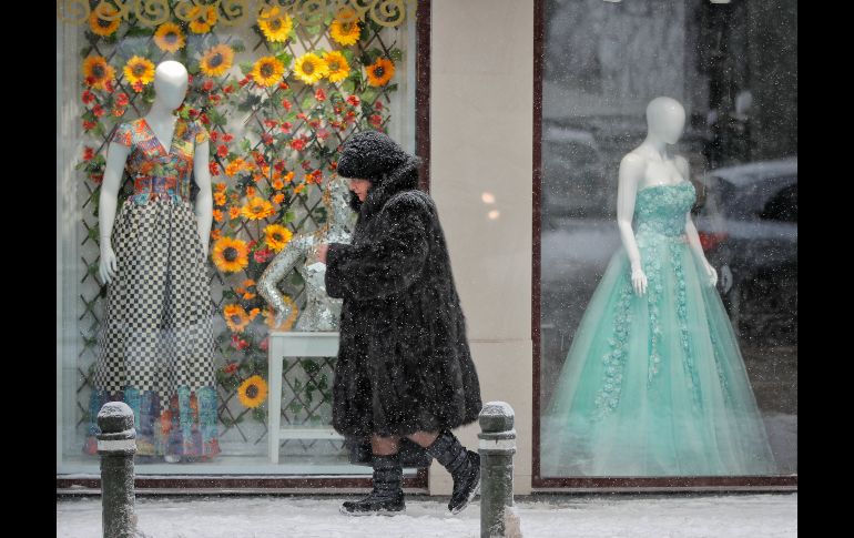 Una mujer camina junto a un aparador en Bucarest, Rumania. El país experimenta un marzo más frío de lo habitual, con nieve y lluvia helada que provocan afectaciones en los transportes.