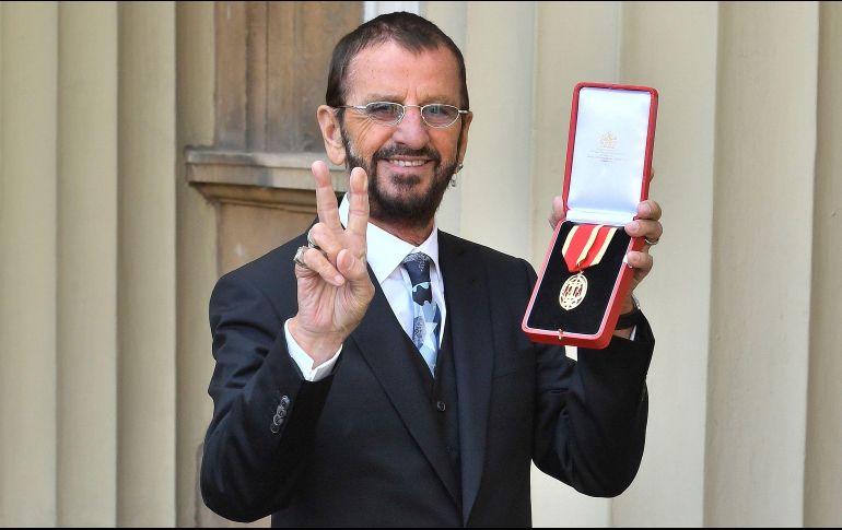 Ringo Starr, exbaterista de los Beatles, posa son su medalla tras recibir el título de caballero del príncipe Guillermo en el Palacio de Buckingham, en Londres. Para la ocasión usó su verdadero nombre, Richard Starkey. AFP/J. Stillwell
