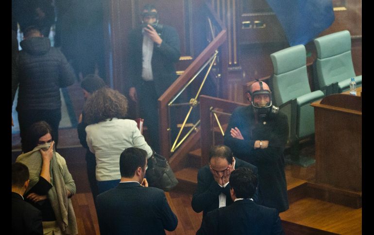Policías usan máscaras mientras legisladores se cubren las caras, luego de que se arrojara una lata de gas lacrimógeno en una sesión parlamentaria en Pristina, Kosovo, la cual tuvo que suspenderse. AP/V. Kryeziu