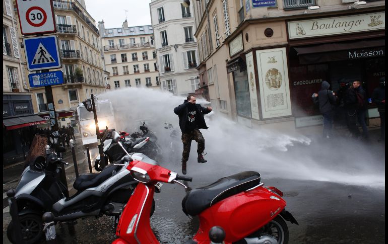 Un hombre salta mientras la policía arroja chorros de aguas durante una manifestación en París. Miles de franceses se manifestaron alrededor del país en protesta contra las reformas del gobierno de Emmanuel Macron. AP/T. Camus