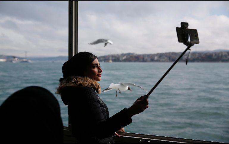 Una mujer se toma una foto mientras cruza el mar Mármara en Estambul, Turquía. AP/L. Pitarakis