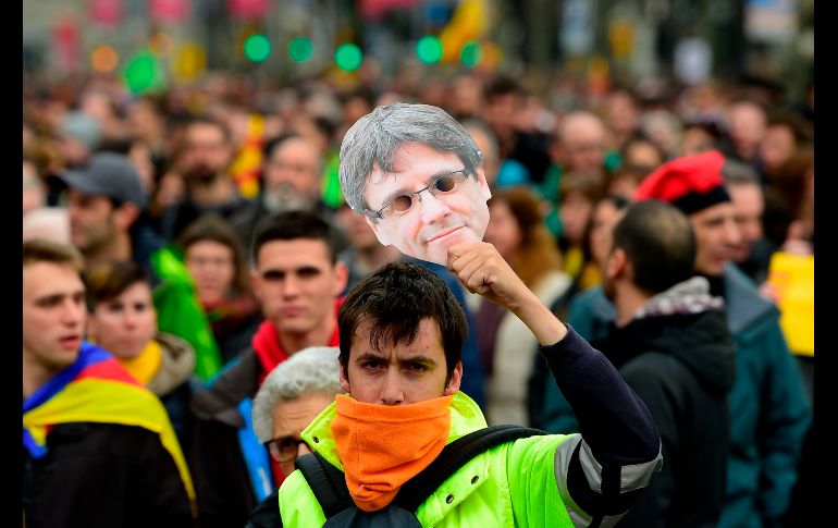 Un manifestante sostiene una máscara de Carles Puigdemont, el expresidente independentista catalán.