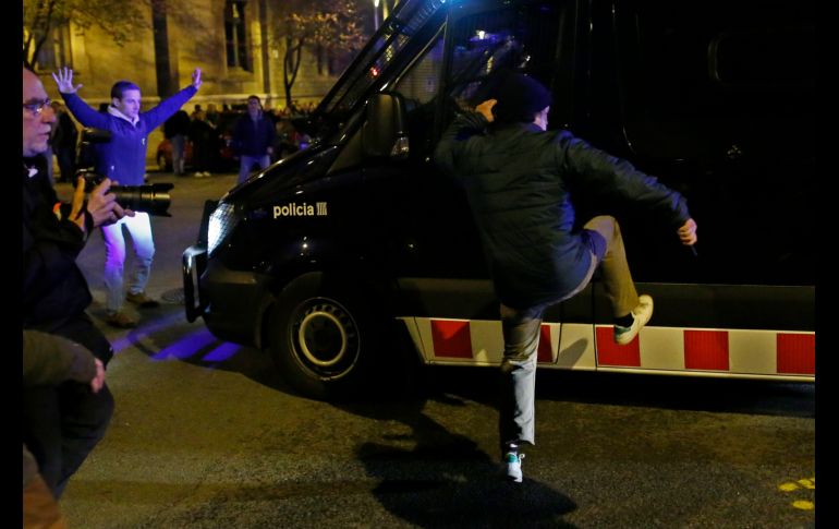 Un hombre patea un vehículo policial.