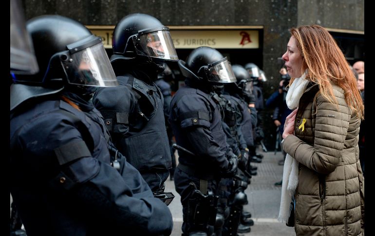 Una mujer llora mientras habla con los agentes que bloquean una vialidad.
