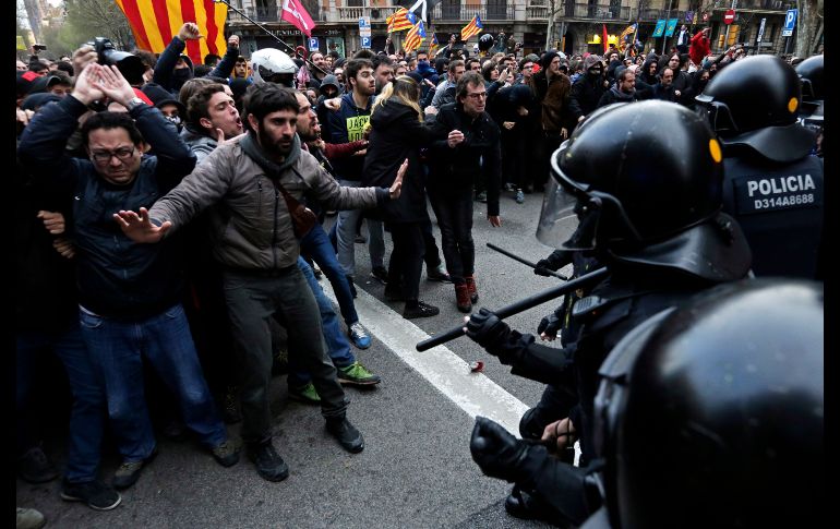 Miembros de los Mossos d'Esquadra impiden el paso de manifestantes en Barcelona, donde independentistas protestan por la detención del expresidente catalán Carles Puigdemont. AP/E. Morenatti