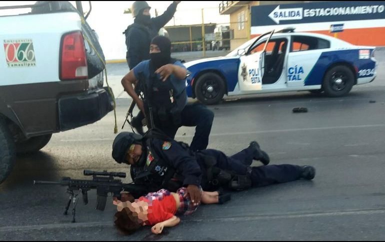 Policías protegen a un niño en medio del tiroteo. EFE/El Mañana