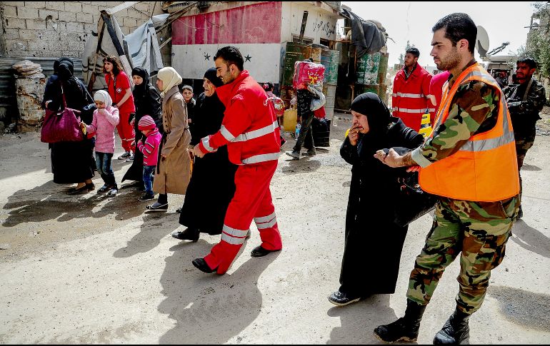Trabajadores de la Media Luna Roja Árabe Siria y soldados sirios ayudan a civiles a abandonar el área de Douma, en la zona de Guta Oriental. EFE/SANA