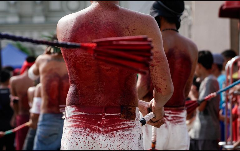 Hombres se fustigan con látigos de cuero en la espalda mientras caminan en procesión. EFE/R. Cristino