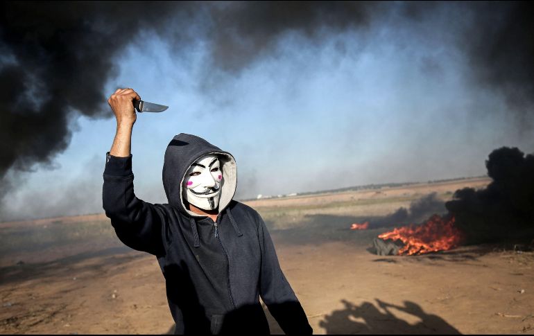 Un manifestante palestino con máscara de Anonymous y un cuchillo se enfrenta con fuerzas de seguridad israelíes en Khan Yunis, en la Franja de Gaza fronteriza con Israel. AFP/S. Khatib