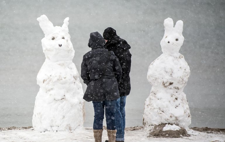 Personas se ven frente a dos conejos de nieve en la isla Fehmarn, al norte de Alemania. AFP/DPA/F. Gambarini
