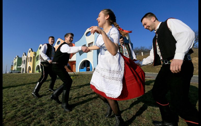 Jóvenes en atuendos tradicionales simulan golpear a una chica con látigos, como parte de un festejo  del lunes de Pascua en  Velke Pavlovice, República Checa. AFP/R. Mica