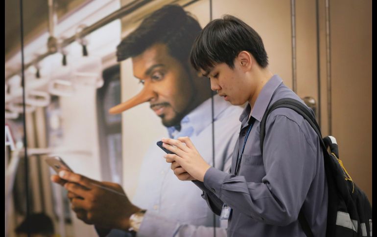 Un usuario del transporte público pasa junto a un anuncio que llama a evitar la difusión de falsas noticias, en una estación de tren en Kuala Lumpur, Malasia. AP/V. Thian