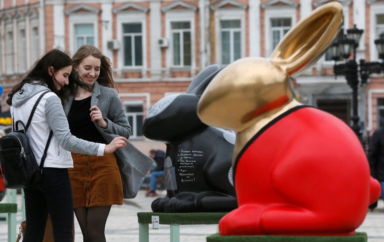 Dos jóvenes observan una escultura que representa un conejo de pascua como parte de una exposición de huevos y conejos de Pascua ante la Catedral de Sofía en Kiev, Ucrania. EFE / S. Dolzhenko