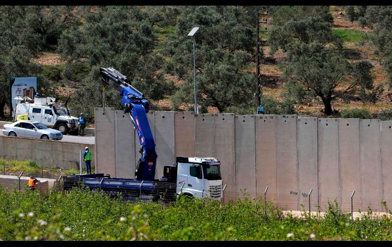 Una grúa en Metula, Israel, instala secciones de un muro de concreto en la frontera con Líbano, mientras fuerzas de Naciones Unidas realizan monitoreo desde el lado libanés. AFP/J. Marey