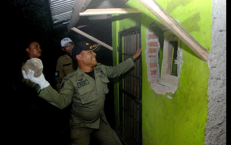Un policía entra a una casa en Cicalengka, Indonesia. Once personas murieron hoy tras consumir licor de contrabando, días despúes de la muerte de 24 personas por el mismo motivo. AFP/T. Matahari