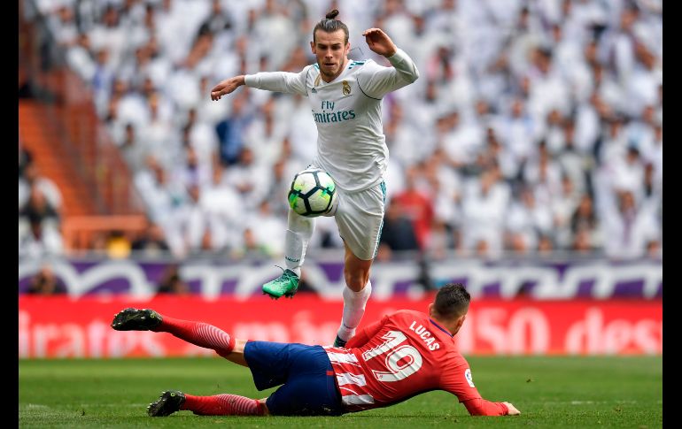 Gareth Bale, del Real Madrid, salta sobre Lucas Hernández, del Atlético de Madrid, en juego de la Liga española disputado en la capital española. AFP/G. Bouys