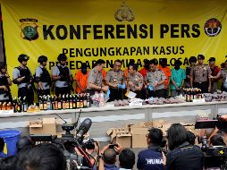 La Policía presentó en la rueda de prensa a seis de las siete personas detenidas, así como varios litros de licor decomisados. AP/T. Syuflana