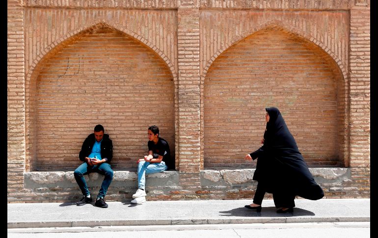 Una mujer pasa junto a hombres que descansan en el puente sobre el río Zayandeh Rud en Isfahan, Irán. El río está ahora seco debido a la extracción del líquido antes de que llegue a la ciudad. AFP/A. Kenare