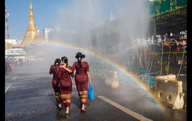 En la celebración del Año Nuevo Budista, un grupo de muchachas con vestidos tradicionales pasan por una zona donde son mojadas como parte de la tradición popular en Rangún, Birmania. AFP / S. Main