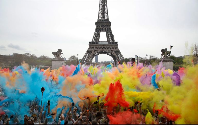 Participantes en una carrera arrojan polvo de colores frente a la torre Eiffel en París, al estilo de la festividad hindú de 