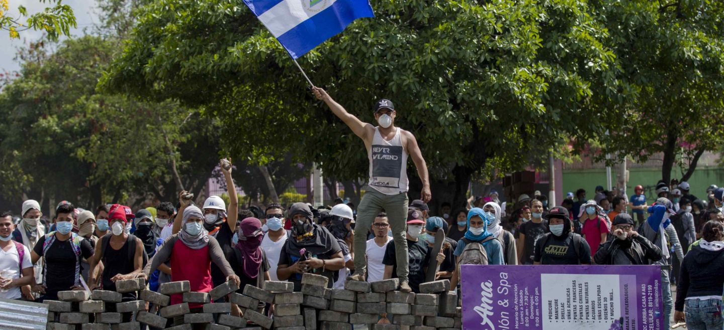 Un joven levanta una bandera de Nicaragua sobre una barricada de adoquines. EFE / J. Torres
