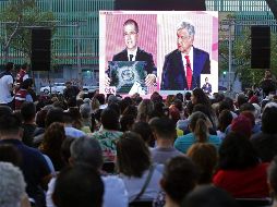 Personas siguen el debate desde una pantalla colocada en la avenida Chapultepec, en Guadalajara. AFP/U. Ruiz