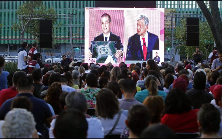 Personas siguen el debate desde una pantalla colocada en la avenida Chapultepec, en Guadalajara. AFP/U. Ruiz