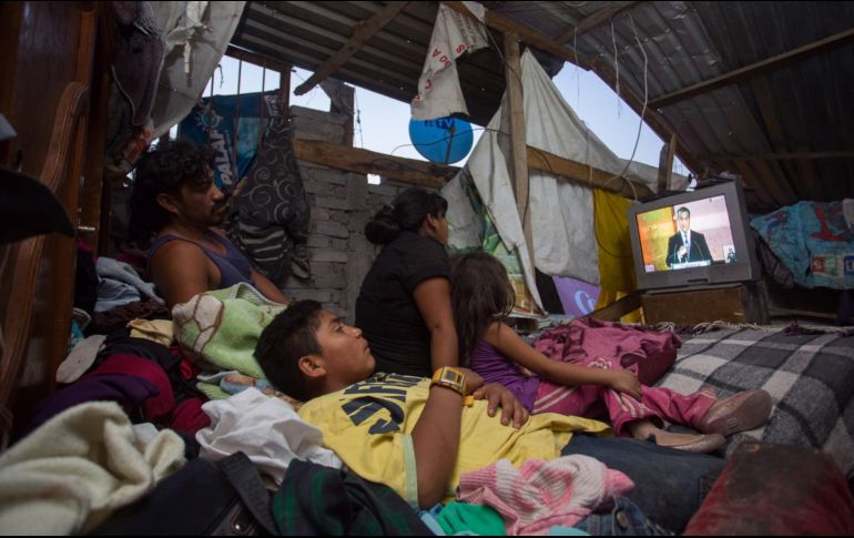 Una familia observa por televisión el primer debate de los candidatos a la Presidencia de México. EFE / L. Granados