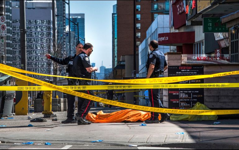 Miembros de la policía de Toronto montan guardia junto a un cuerpo cubierto por una manta, en el lugar donde una camioneta ha arrollado a varios peatones en Toronto, Canadá. Al menos 9 personas resultaron muertas y 16 heridas. AP/The Canadian Press/A. Elkaim