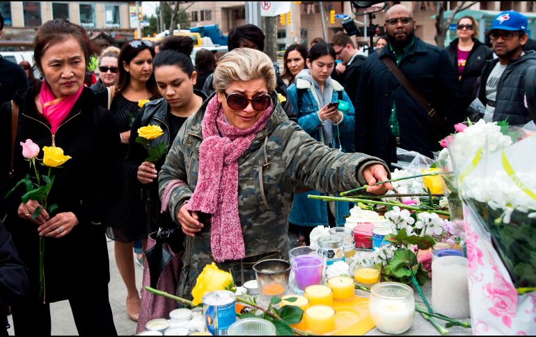 Mujeres dejan flores en memoria de las víctimas del atropellamiento ocurrido ayer en este sitio de Toronto, Canadá. Un conductor arrolló intencionalmte a peatones y dejó 10 muertos. AP/The Canadian Press/N. Denette