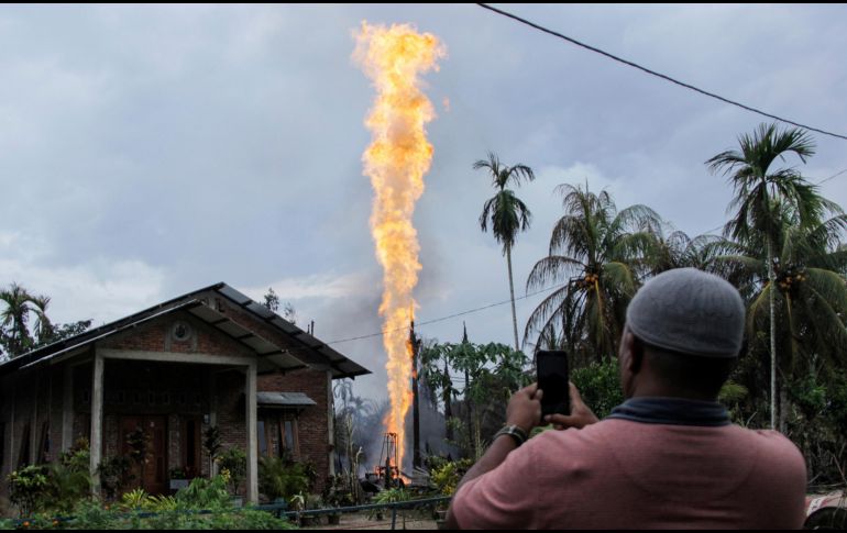 Un hombre toma fotos de un pozo petrolero en llamas en Pasir Putih, Indonesia. El pozo recién perforado de forma ilegal explotó esta mañana y provocó la muerte de al menos 15 personas. AP/Z. Maulana