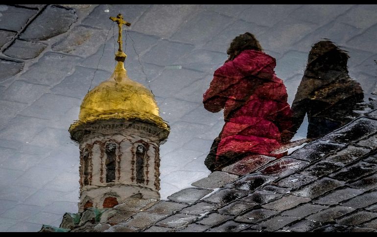 Mujeres se reflejan en un charco en la plaza Roja de Moscú, Rusia. AFP/Y. Kadobnov