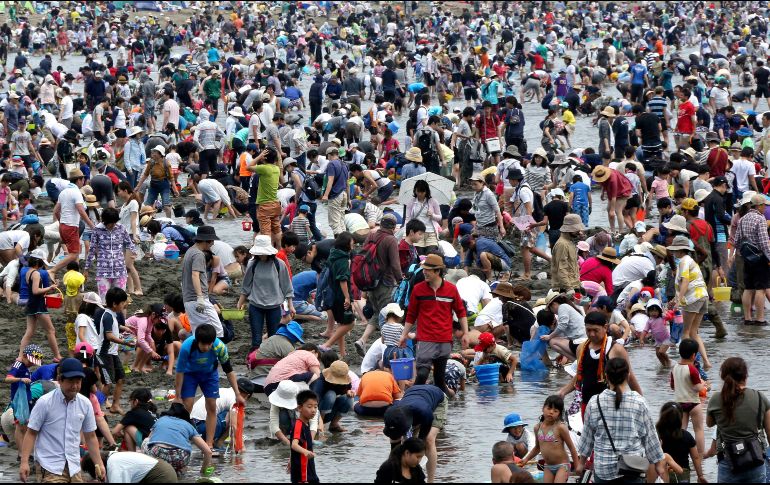 Personas buscan almejas en una playa de Yokohama, Japón. Miles de personas abarrotaron el sitio en el inicio de un periodo vacacional de una semana, la llamada 
