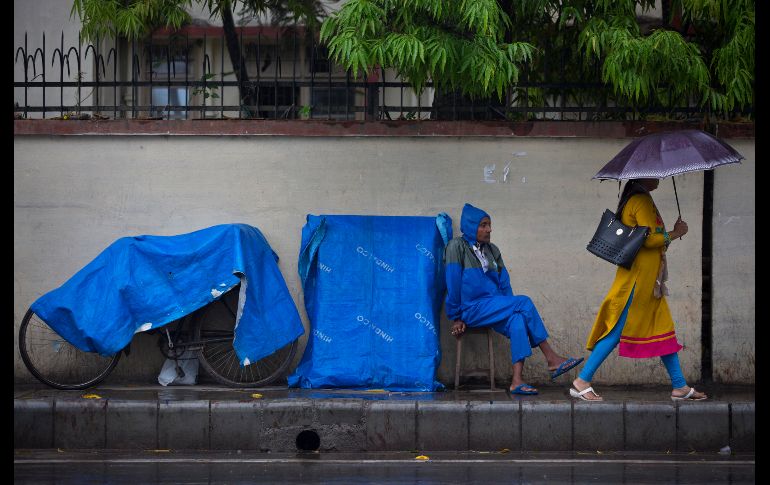 Un vendedor callejero aguarda con su mercancía cubierta mientras llueve en Gauhati, India. AP/A. Nath