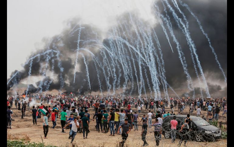 Palestinos huyen del gas lacrimógeno arrojado durante enfrentamientos con fuerzas de seguridad israelíes en la frontera con Franja de Gaza, en el sexto día consecutivo de protestas en demanda del derecho de volver a sus viviendas históricas. AFP/M. Hams