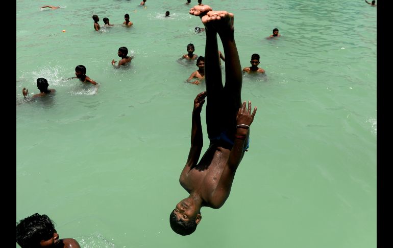 Jóvenes juegan en una alberca durante un día caluroso en Chennai, India. AFP/A. Sankar