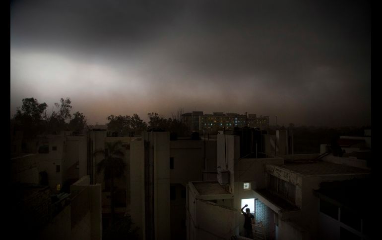 Un hombre se para en el balcón de su departamento durante una tormenta repentina en Nueva Delhi, India. Aún faltan seis semanas para el incio del monzón. AP/M. Swarup