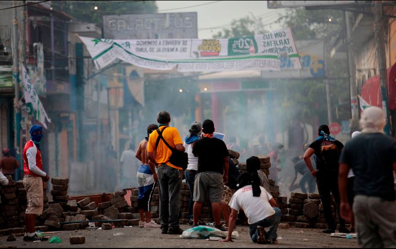 Protestantes parapetados tras una barricada en un choque con la policía. AFP/D.Ulloa