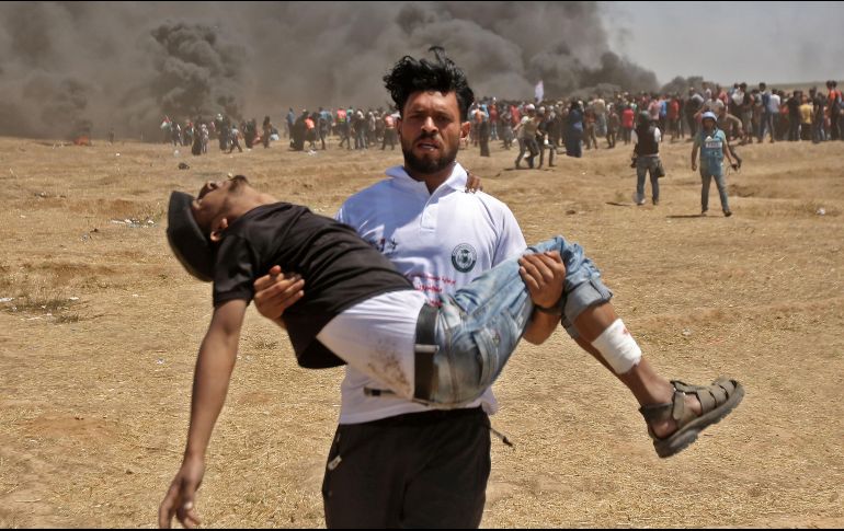 Un palestino carga a un manifestante herido durante los enfrentamientos con las fuerzas israelíes cerca de la frontera entre la Franja de Gaza e Israel. AFP / M. Hams