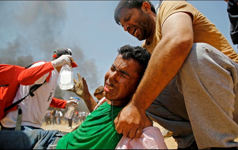 Un palestino asiste a un manifestante herido durante los enfrentamientos con las fuerzas de seguridad israelíes cerca de la frontera entre Israel y la Franja de Gaza. AFP / M. Abed