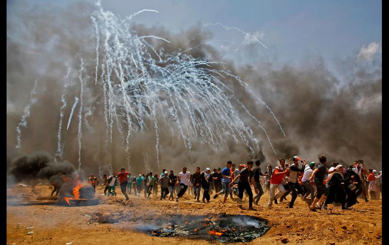 Palestinos que protestan en la frontera entre la Franja de Gaza e Israel huyen de gas lacrimógeno. Miles de palestinos protestaron a lo largo de la frontera, provocando los disparos del Ejército israelí.