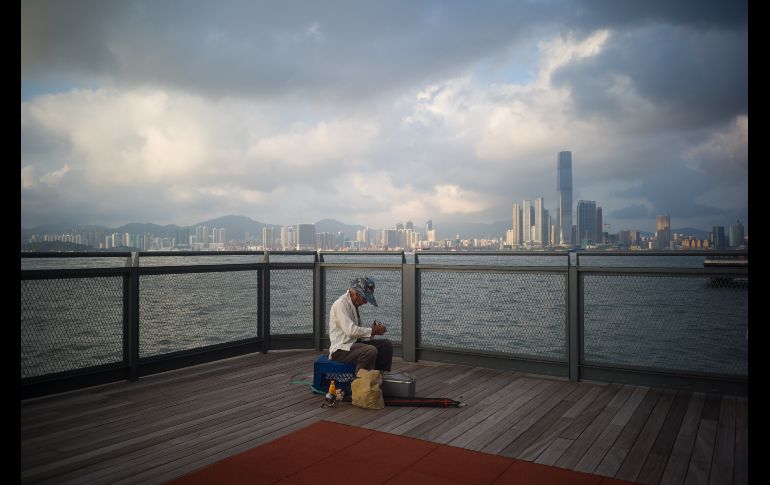 Un anciano empaca su equipo de pesca desde un mirador en el puerto Victoria Harbour de Hong Kong. AFP/A. Wallace
