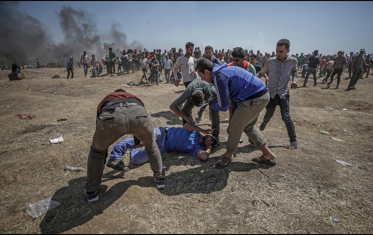 Manifestantes palestinos tratan de ayudar a un herido durante enfrentamientos tras una protesta cerca de la frontera con Israel. EFE/M. Saber