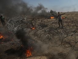 Manifestantes palestinos tratan de tirar el alambre instalado por el ejército israelí a lo largo de la frontera. EFE/M. Saber