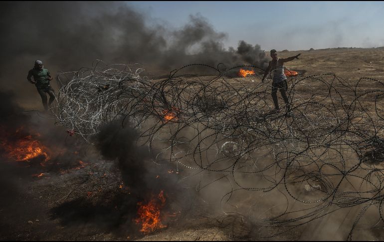 Manifestantes palestinos tratan de tirar el alambre instalado por el ejército israelí a lo largo de la frontera. EFE/M. Saber